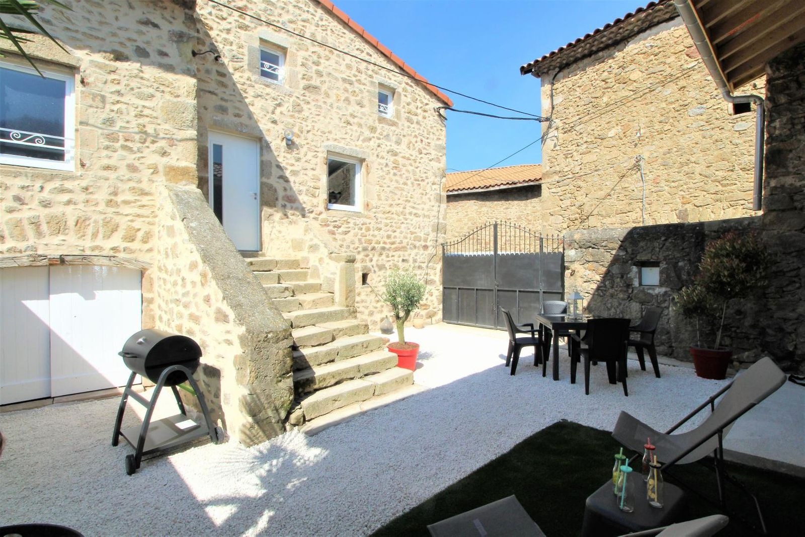 Cour privative avec espace détente, coin repas et barbecue charbon de bois 