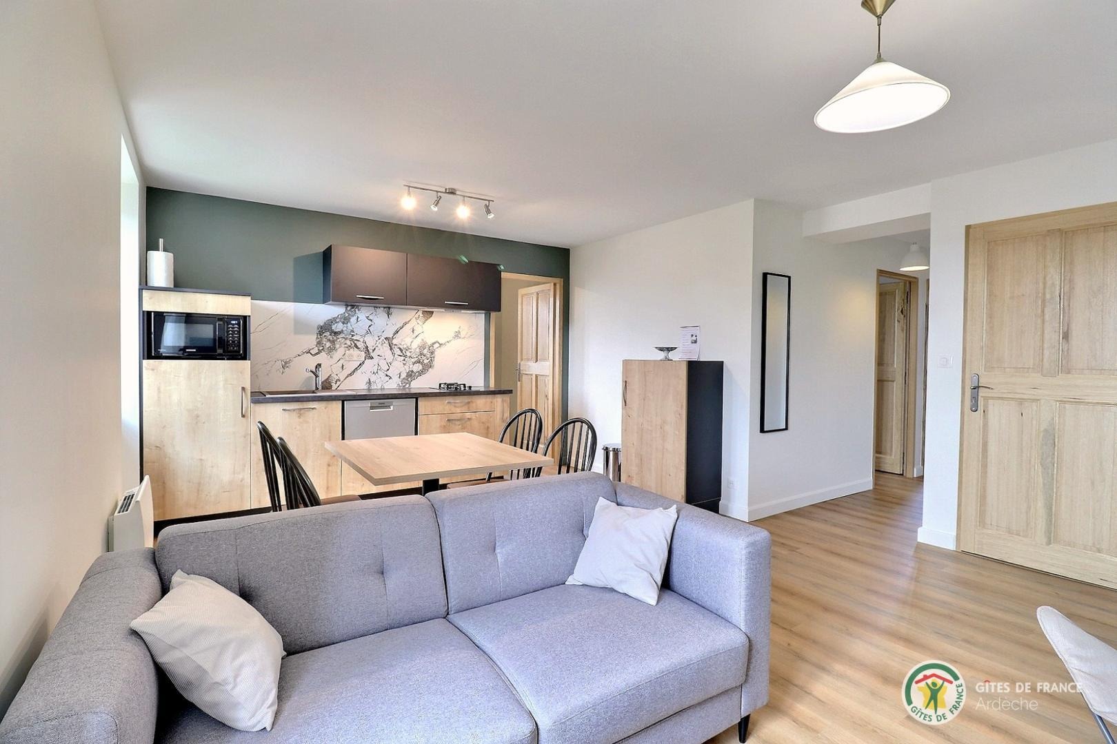 Pièce de vie avec coin cuisine équipée et salon