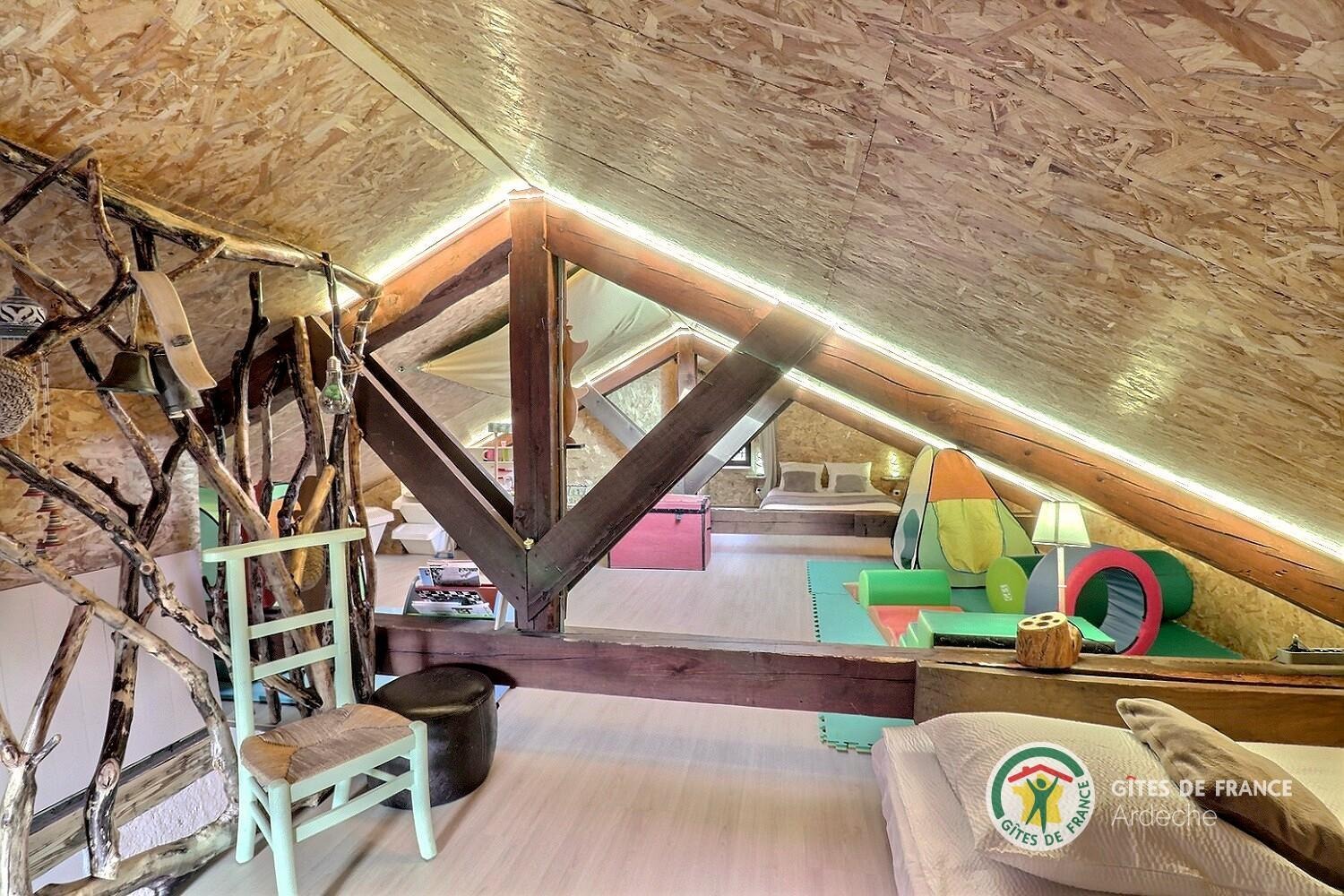 Espace mansardé sous les toits avec couchages et salle de jeux pour les enfants