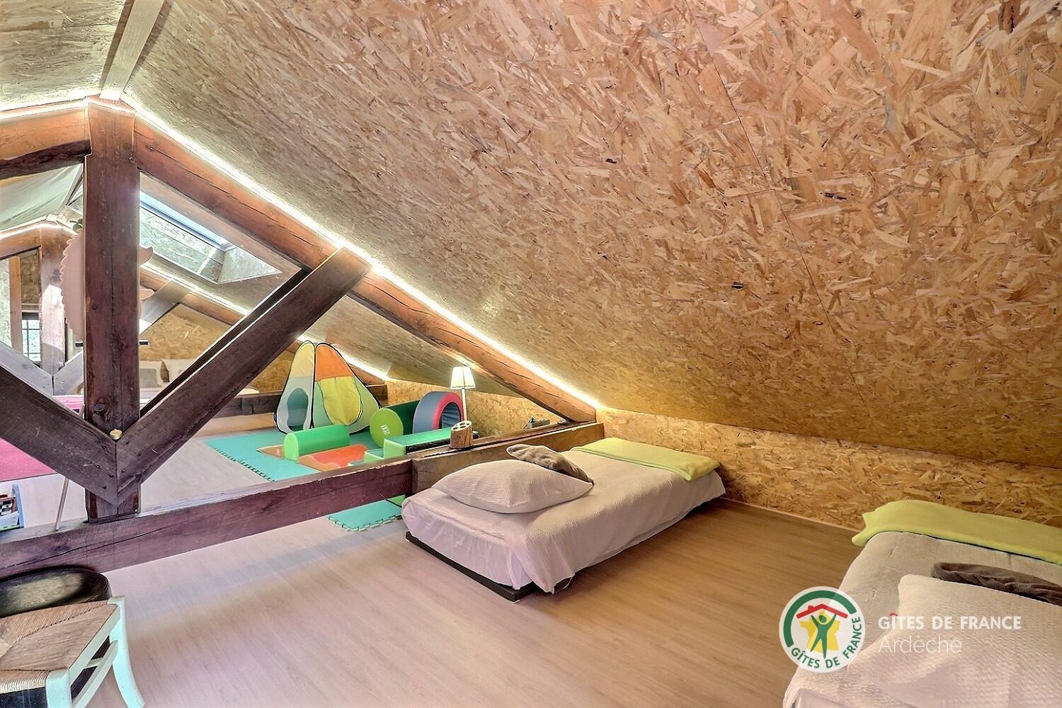 Espace mansardé sous les toits avec couchage et salle de jeux pour les enfants