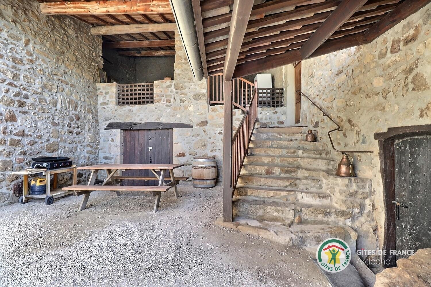 Escalier d'entrée du gîte, plancha et table pour vos repas en plein air
